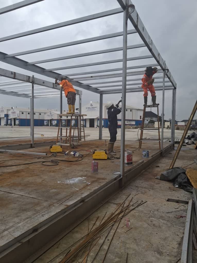 Crew in full PPE mounting structural steel roof beams